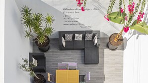 A modern outdoor seating area with a sofa, cushions, and a yellow cabinet. There are potted plants and a glass railing. - TOI ET MOI -  our reviews speek for us ! (Ponta Delgada)