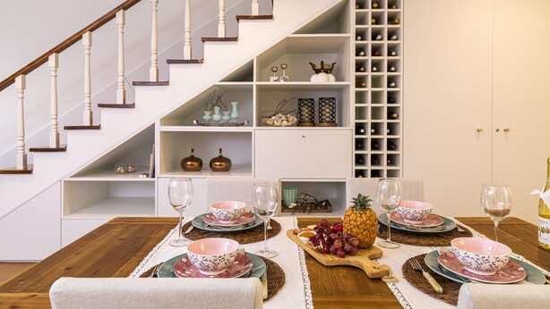 A dining area with a wooden table set for four, surrounded by white shelves with decorative items and a wine rack. - TOI ET MOI -  our reviews speek for us ! (Ponta Delgada)