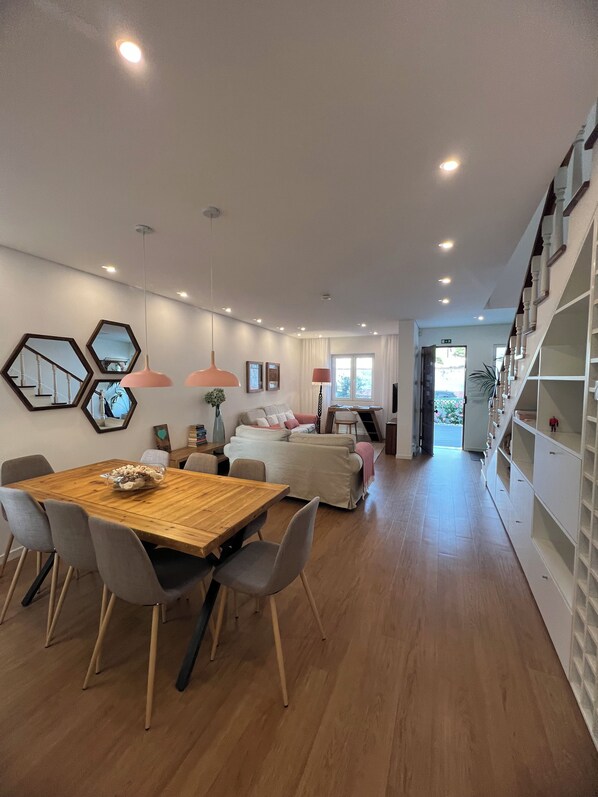 A modern interior with a dining area, a sofa, and a staircase leading to a second floor.