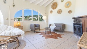 A spacious living area with a large arched window, a fireplace, and a cowhide rug.