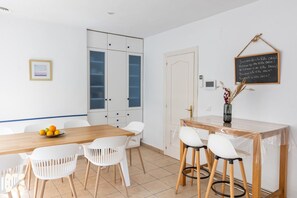 A modern kitchen with white cabinets, a wooden table, and white chairs.