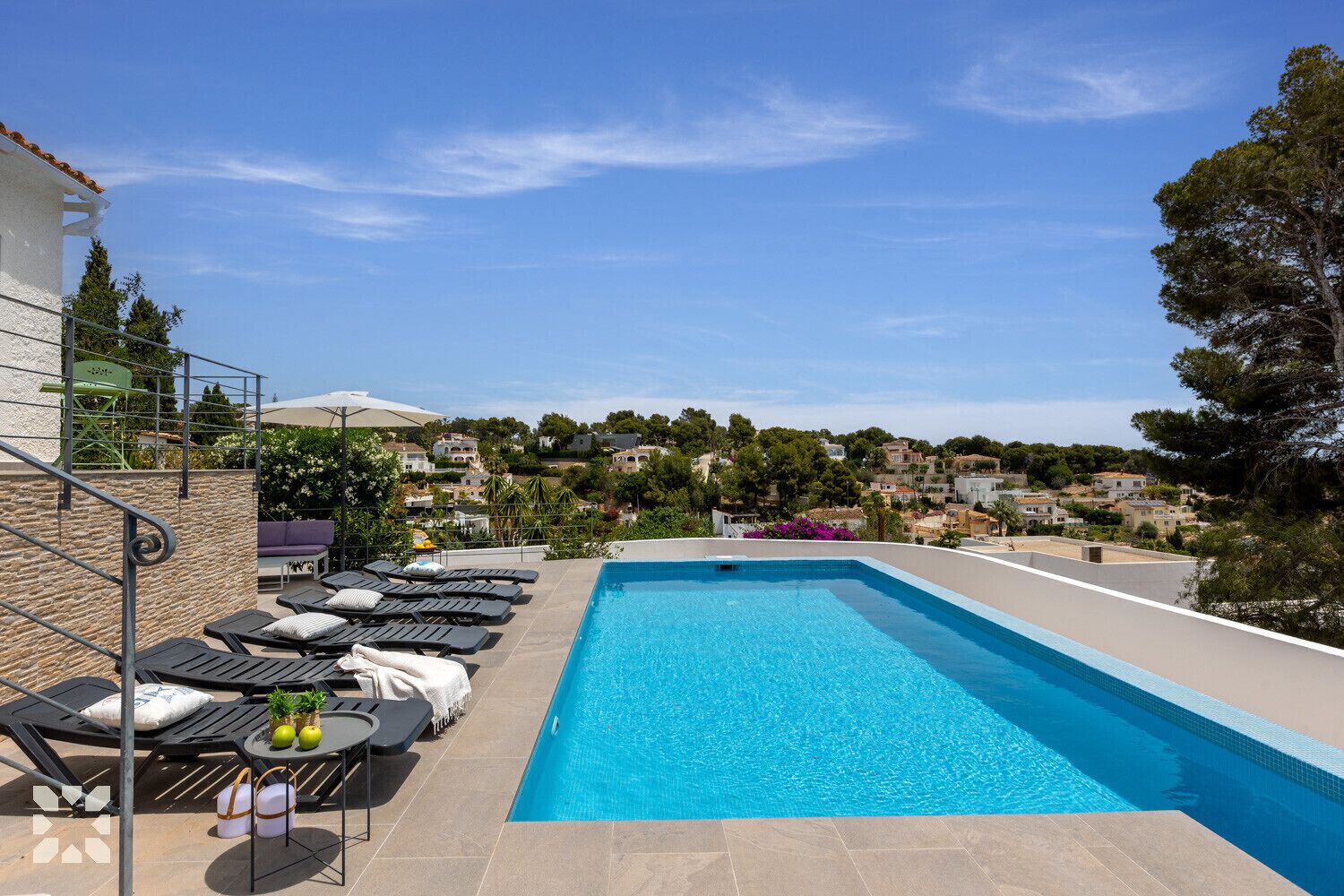 Una piscina en la azotea con sillones de descanso y vistas a un barrio residencial.