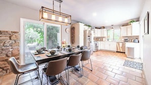 A spacious kitchen with a large dining table, modern appliances, and a stone accent wall.