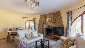 Una sala de estar con chimenea de piedra, un televisor y una araña.