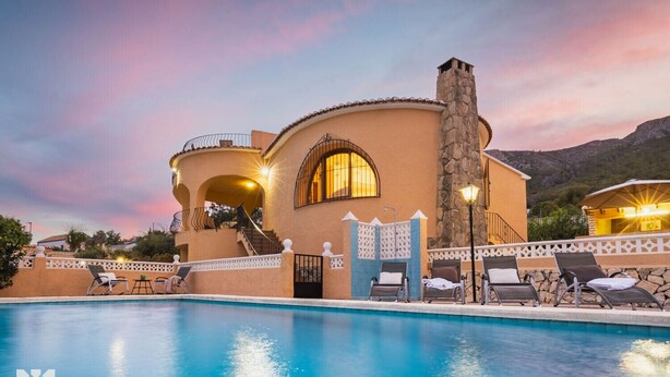 Un resort con piscina, chimenea de piedra y un edificio curvo con ventanas arqueadas.