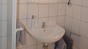 Ett badrum med ett vitt handfat, en spegel och en handdukshängare.