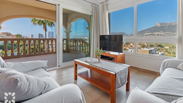 A balcony with a TV, seating, and a view of the city. - Villa SOCRATES by Abahana Villas (Calpe)