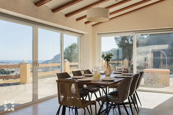 A dining area with a table set for six, large sliding glass doors, and a view of the landscape.