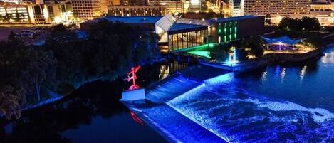 A waterfront hotel with a water feature, modern architecture, and a city skyline in the background.
