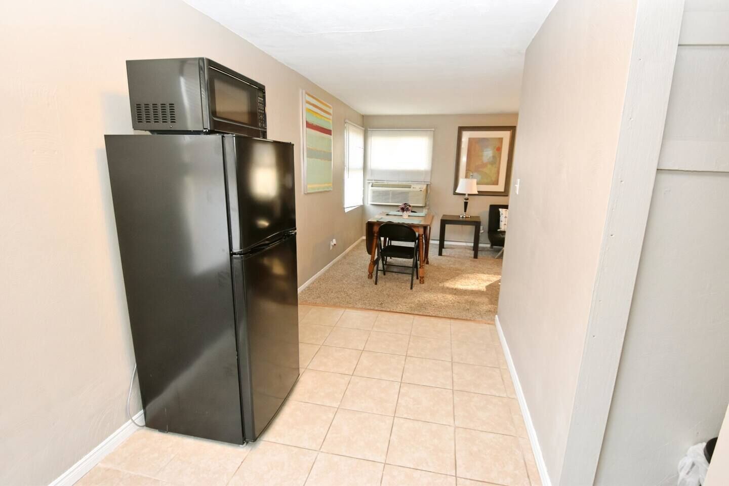 A compact kitchen with a refrigerator, microwave, and a dining area with a table and chairs.