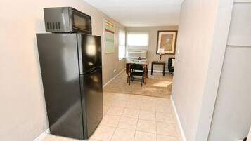 A compact kitchen with a refrigerator, microwave, and a dining area with a table and chairs.