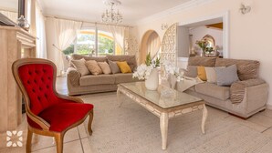 Un salón amplio con dos sofás, una butaca tapizada en rojo y una mesa de centro.