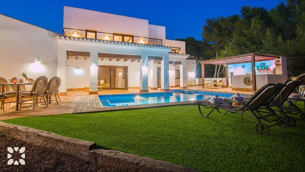 Una casa moderna de dos plantas con piscina, zona de estar exterior y un bar.