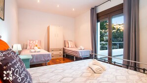 Un dormitorio con dos camas, un armario y un balcón con vistas.