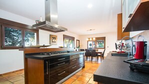 Una cocina moderna con una isla central, electrodomésticos integrados y un comedor con luz natural.