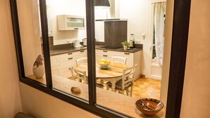 Een moderne keuken met een eettafel, stoelen en een raam dat uitzicht biedt op de kamer.