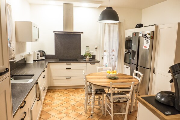 Una cocina compacta con una mesa de comedor, sillas, una cafetera, un refrigerador y un microondas.