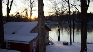 Lumipeitteinen mökki, joka sijaitsee lähellä puita ympäröivää järveä.