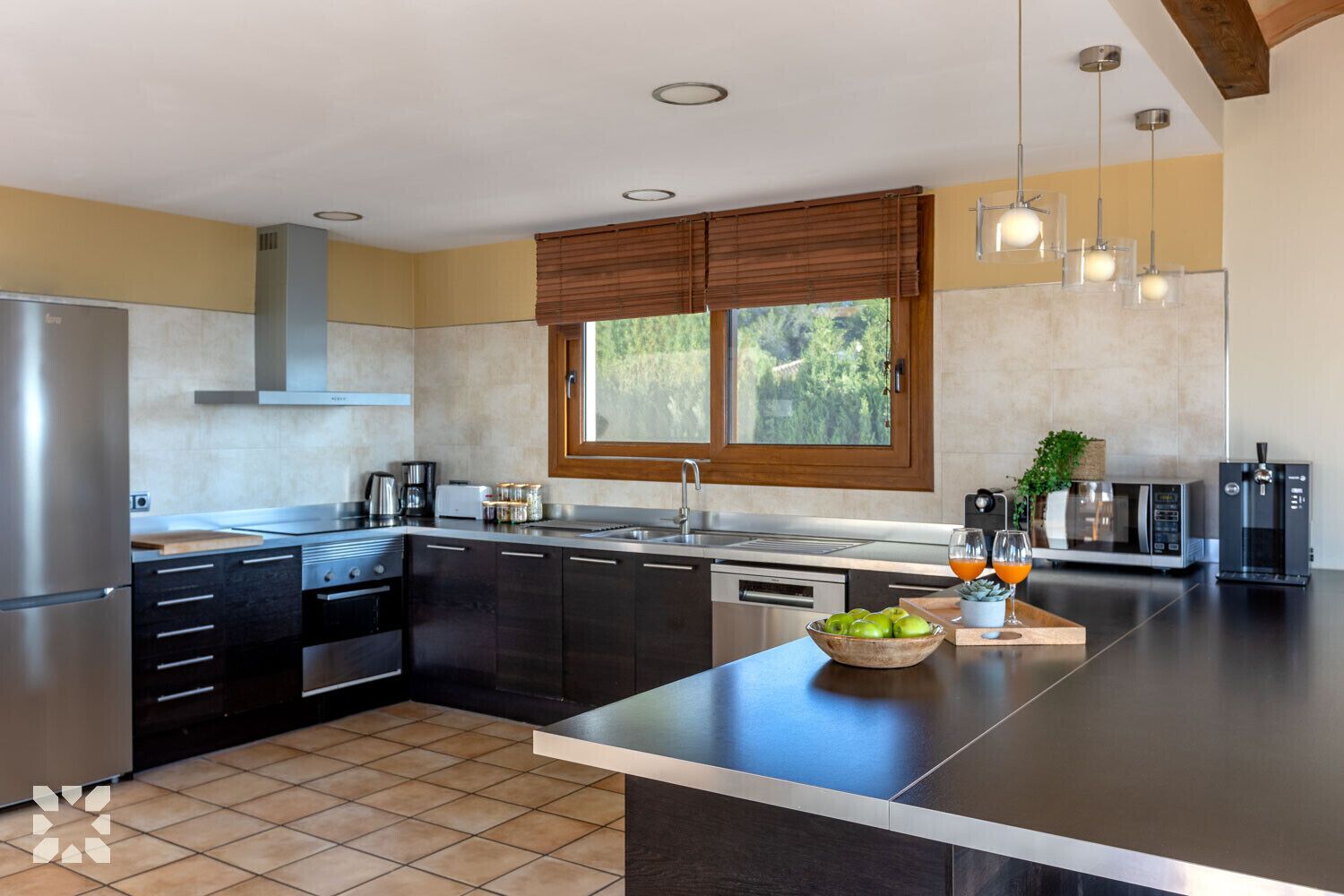 A modern kitchen with a central island, stainless steel appliances, and a large window providing natural light.