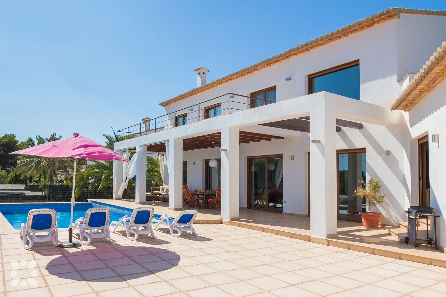 A modern villa with a pool, outdoor seating, and a covered patio area.