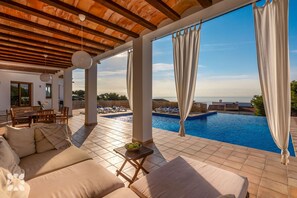 Ein sonnendurchfluteter Außenbereich mit Sitzgelegenheiten und Pool, mit Blick auf eine reizvolle Landschaft.