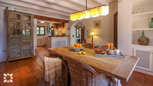Un comedor rústico con una mesa de madera, sillas de mimbre y un colgante.