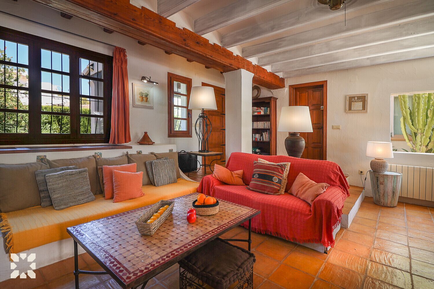 Un salon chaleureux avec un canapé rouge, une table basse à motifs et une bibliothèque.