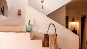 Una escalera con pared texturizada, una escultura colgante, una botella verde y un bolso tejido.