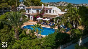 Un resort con piscina rodeada de palmeras y sillas de descanso.