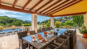 Un espace extérieur aménagé pour les repas, avec une piscine, des meubles en osier et une vue sur le paysage.