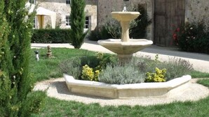 A stone fountain in a garden with a building in the background. - Cottage in the countryside with pool near the Marais Poitevin (Xaintray)