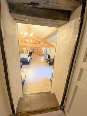 A narrow stairway leading to a spacious living area with a high ceiling and exposed wooden beams. - Cottage in the countryside with pool near the Marais Poitevin (Xaintray)