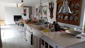Eine moderne Küche mit einer großen Kochinsel, Edelstahlgeräten und einem Holzvitrine mit dekorativen Tellern.