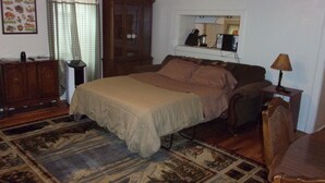 Un dormitorio con una cama, un armario de madera, un escritorio, una silla y una alfombra.