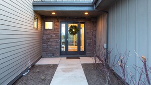 A modern house entrance with a stone facade, a concrete pathway, and a wreath on the door. - SPACIOUS ~ 24-hr staff ~ clean + modern ~ wifi ~ parking ~ hot tub ~ firepit 🐶 (Bend)