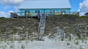 A two-story building with a blue exterior and a white roof, featuring a staircase leading up to a balcony. - Oceanfront Luxury House with Stunning Views (Emerald Isle)