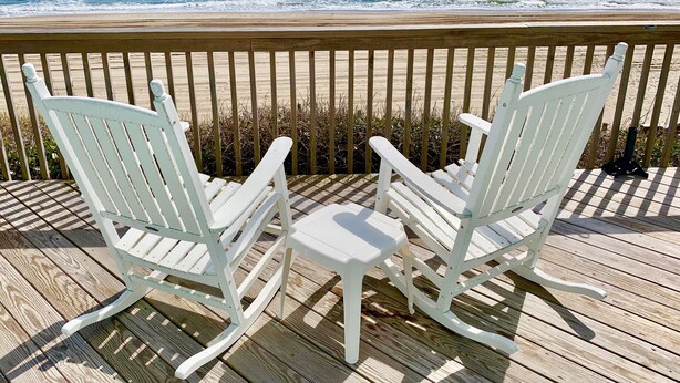 Two white rocking chairs on a wooden deck overlooking the ocean. - Oceanfront Luxury House with Stunning Views (Emerald Isle)