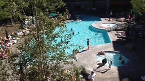 Un espace piscine comprenant plusieurs piscines, des chaises longues et des parasols.