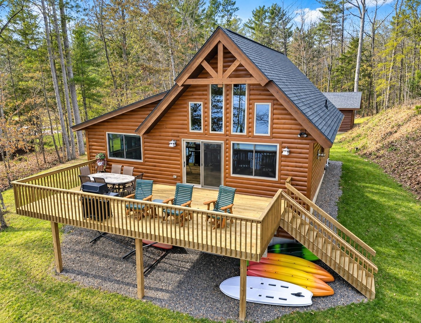 A log cabin with a deck, outdoor seating, and kayaks.