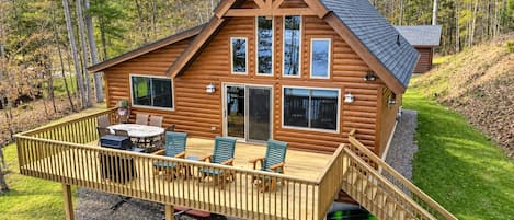 A log cabin with a deck, outdoor seating, and kayaks.