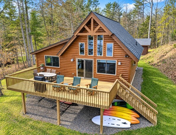 Una cabaña de madera con terraza, mobiliario exterior y kayaks.