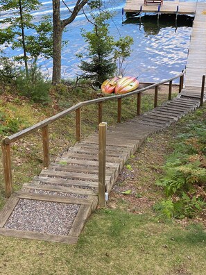 A wooden staircase leading to a dock over a body of water, surrounded by trees and greenery. - Crystal Clear Water, UTV Trail & Free Firewood! (Eagle River)