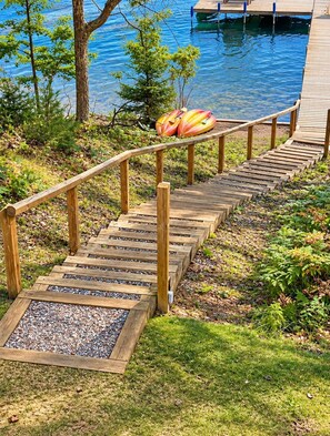 A wooden deck leading to a pool area with kayaks.