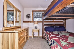 A bedroom with a bunk bed, wooden dresser, bedside table, lamp, and a quilt. - Crystal Clear Water, UTV Trail & Free Firewood! (Eagle River)