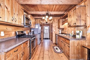 A wooden interior with a kitchen area featuring a stove, microwave, and refrigerator. - Crystal Clear Water, UTV Trail & Free Firewood! (Eagle River)