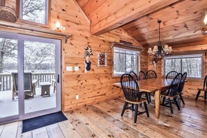 A wooden cabin interior with a dining table and chairs, a chandelier, and a sign reading 'Cory Retreat'.