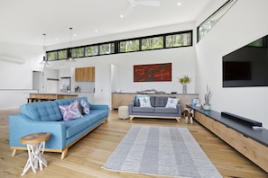 A modern living room with a blue sofa, grey sofa, and a flat-screen TV.