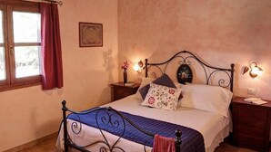 Ein Schlafzimmer mit Bett, Nachttischen, einem Fenster mit Vorhängen und Wandleuchten.
