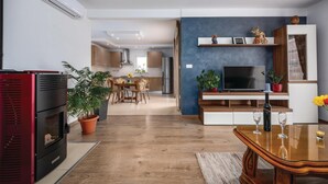 Una sala moderna con televisor, mesa de comedor de madera y chimenea roja.