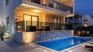 A modern two-story house with a swimming pool, outdoor seating, and a stone facade. - VILLA NICOLINA - AP MARIELLA PRIVATE SUN DECK WITH JACUZZI (Kaštel Novi)